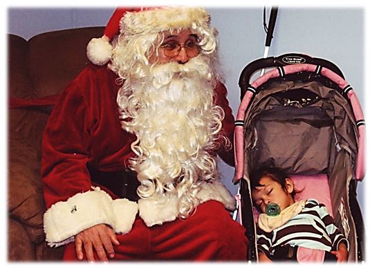 Santa sitting next to a sleeping baby
